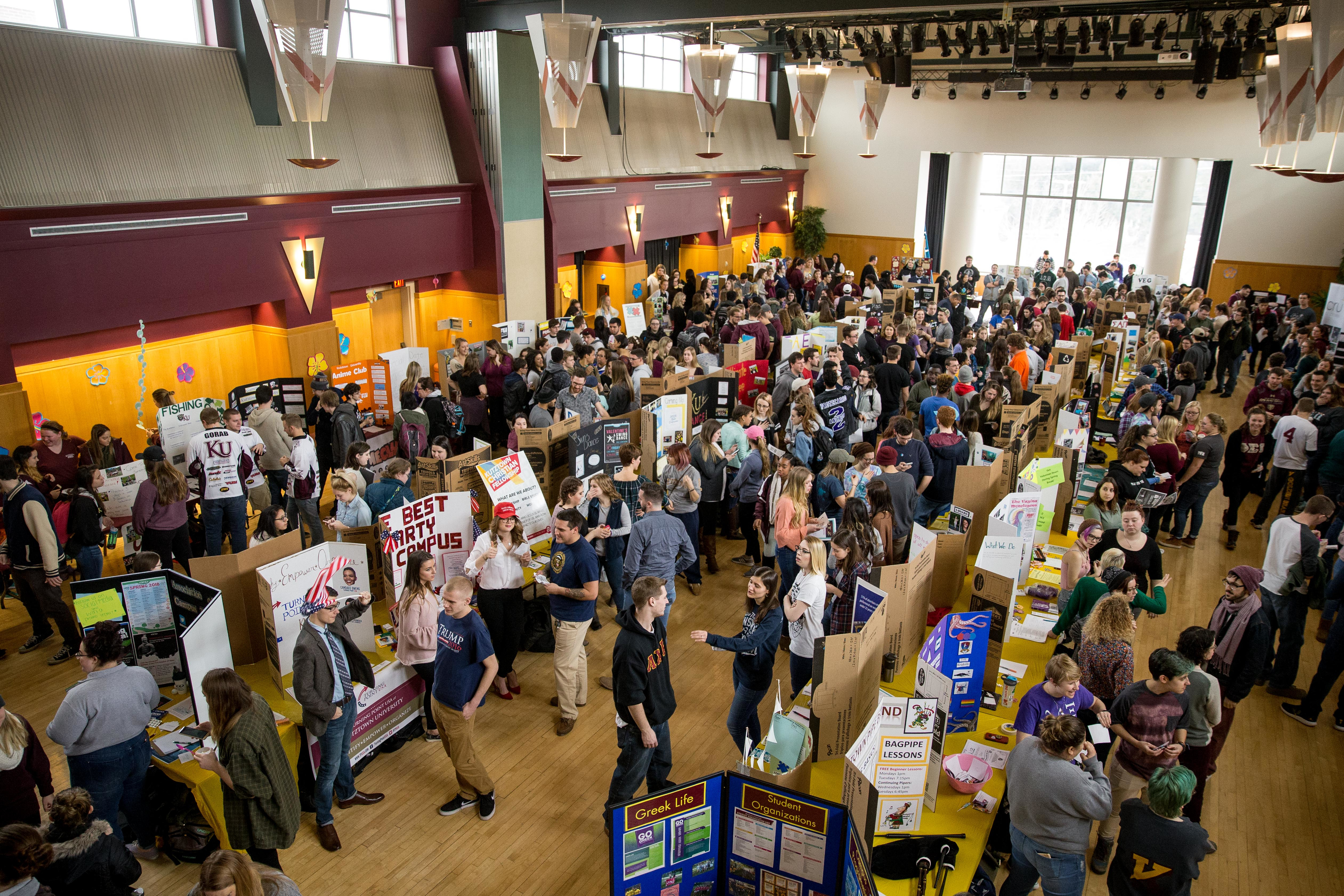 overview photo of large room with many students exploring tables of information about student organizations