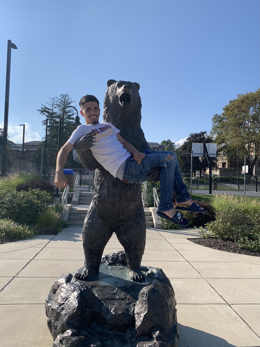Isaiah Rivas in the arms of the golden bear statue