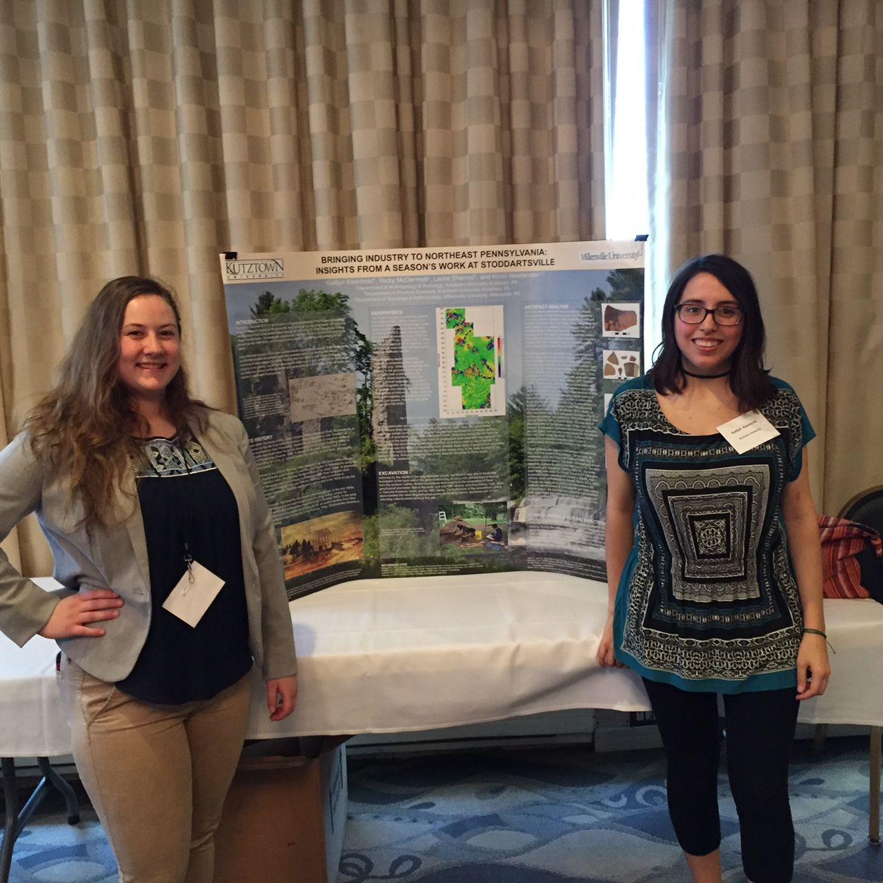 Two female students standing on either side of their research presentation on "Bringing industry to Northeast Pennsylvania: Insights from a season's work at Stoddartsville."