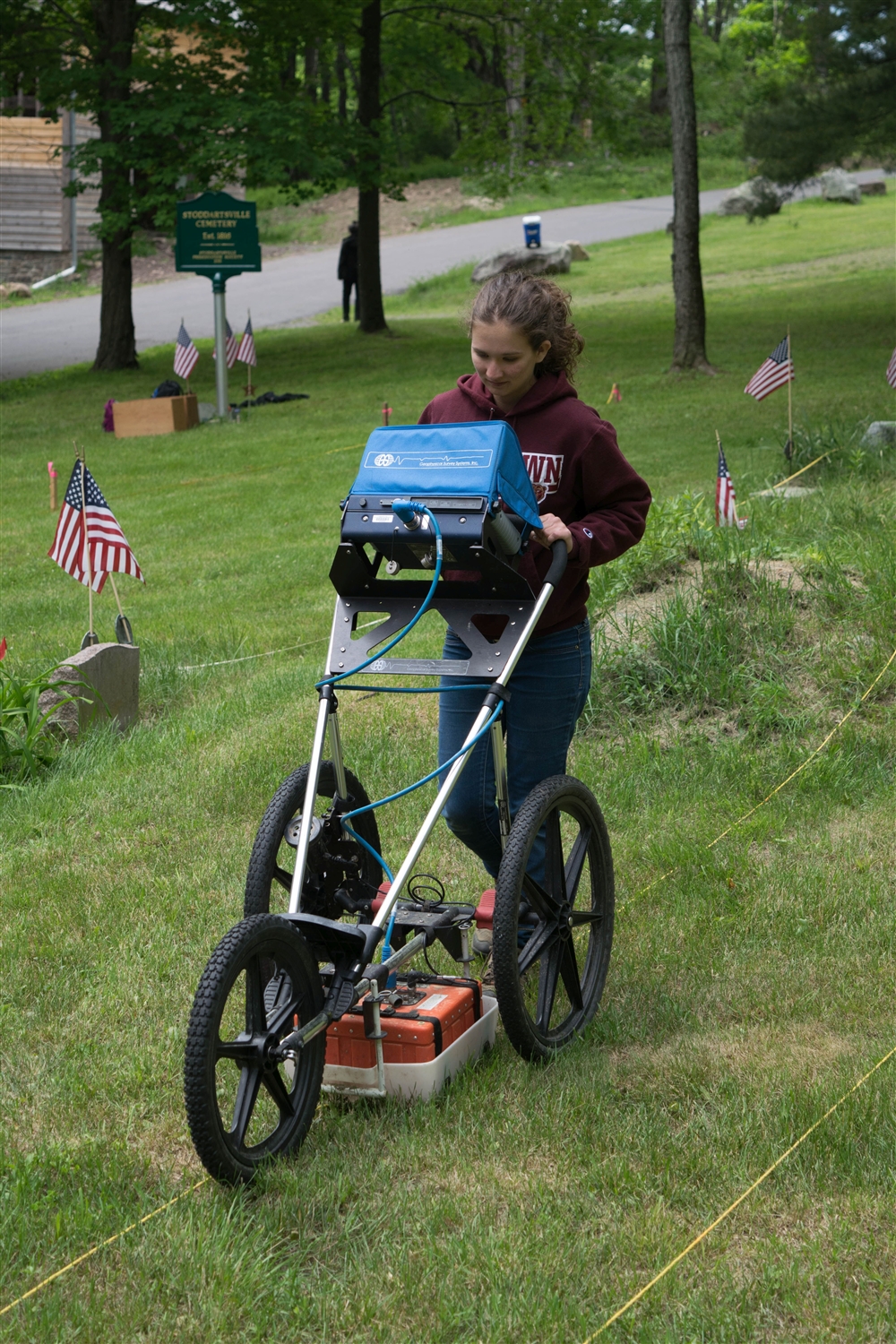 Student pushing a cart with a scanning computer through a field