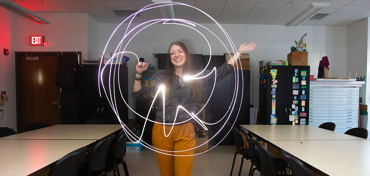 Female student in classroom, using light pen to create pattern.