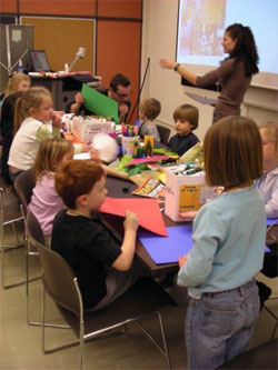 Educator with elementary school students at a craft table 