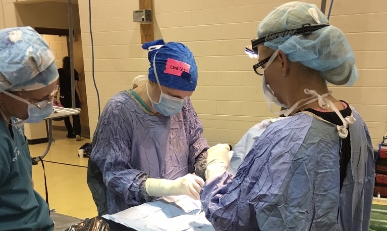 Three students in scrubs performing a practice operation