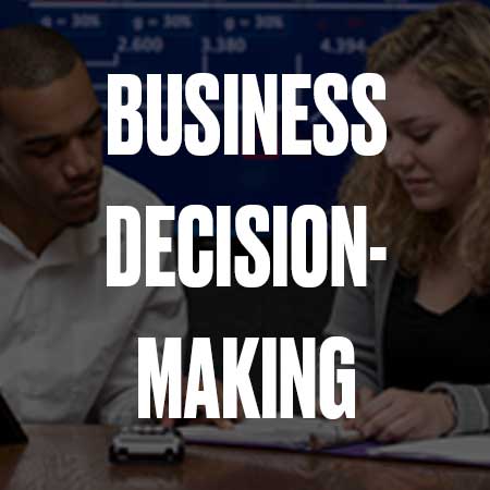 A black man and white woman sitting at a desk working on a computer with a grey overlay and the words Business Decision-Making Graduate Certificate in bold white lettering on top