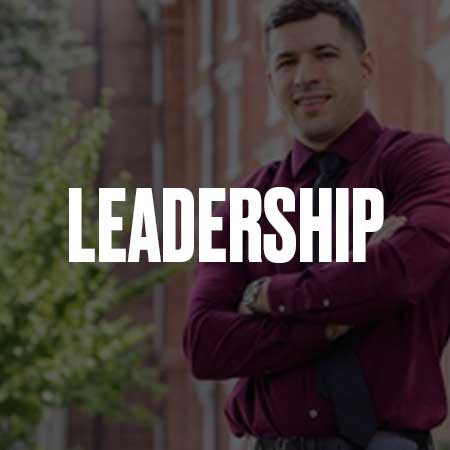 A white man standing outside with arms crossed with a grey overlay and the words Leadership Graduate Certificate in bold white lettering on top