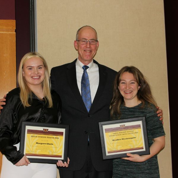 Margaret Davis and Heather Mastrangelo holding their awards and smiling next to Dr. Walker 