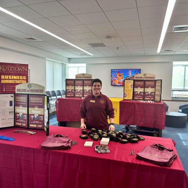 DBA Student in front of maroon and gold posters with major information