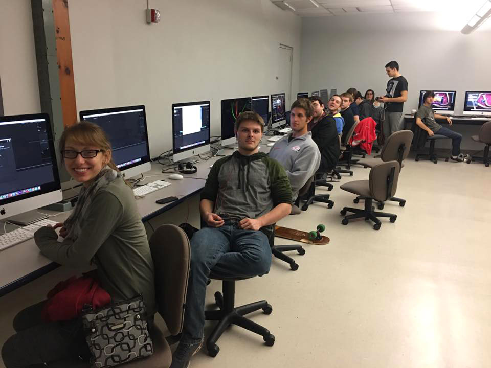 Students smiling at their seats in a film editing lab