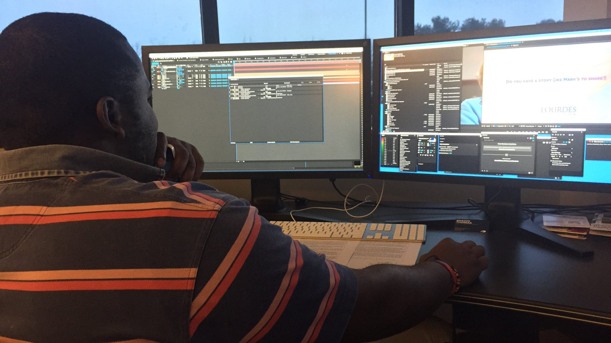 Male student working with video editing software on a dual-monitor desktop. 