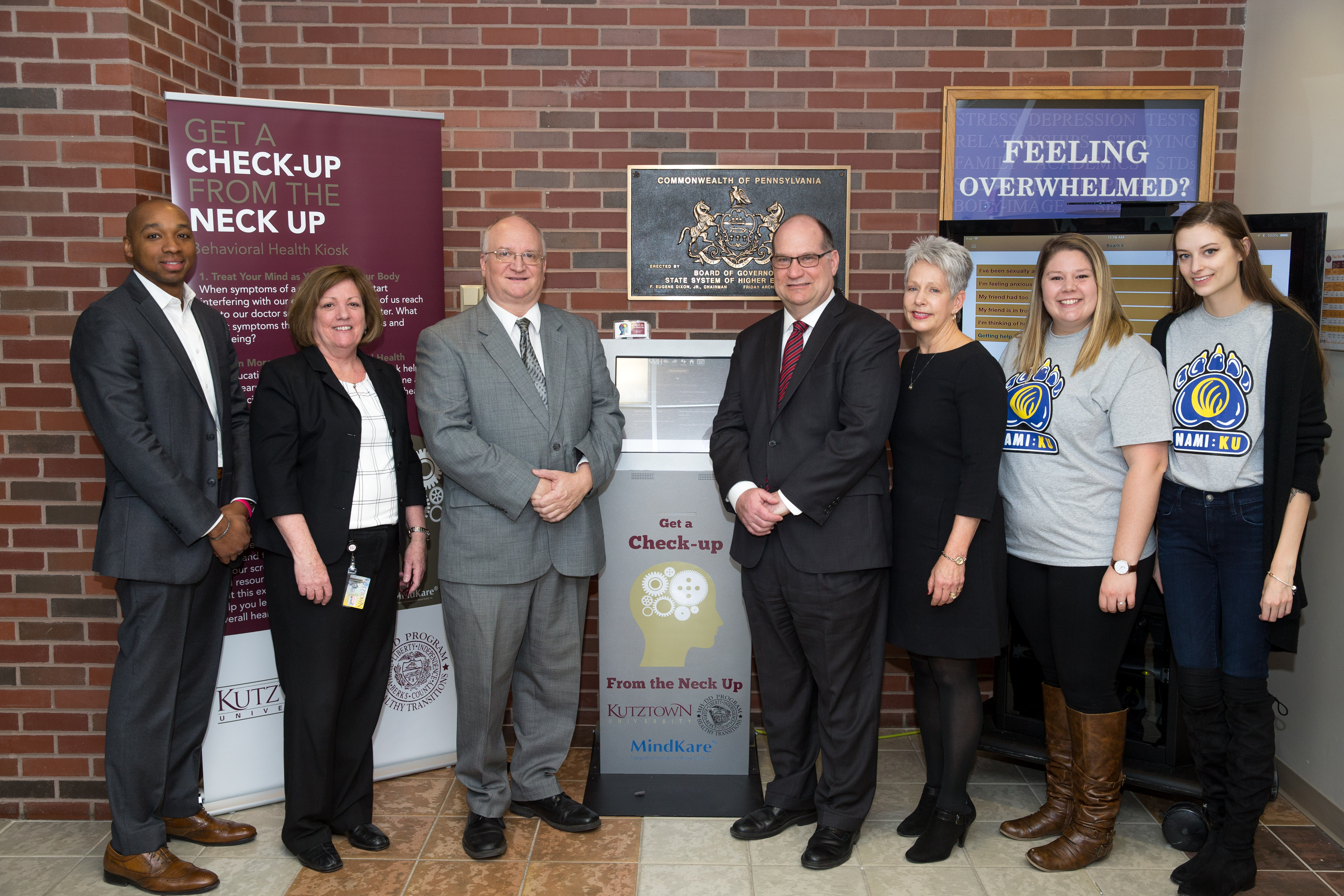 President Hawkinson, Staff, and Students standing on either side of the MindKare mental health kiosk 