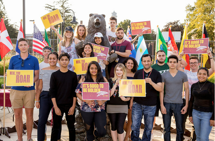 big group of diverse students smiling holding KU signs outside