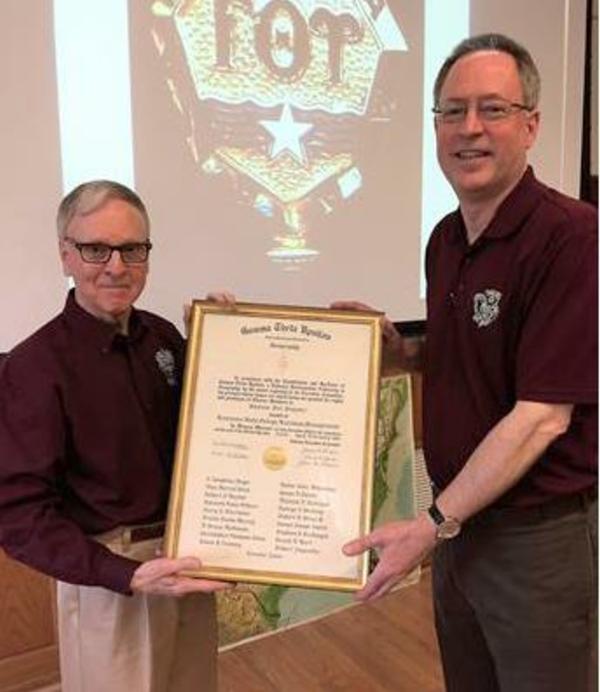 Two male faculty members holding framed Gamma Theta Upsilon charter documents 