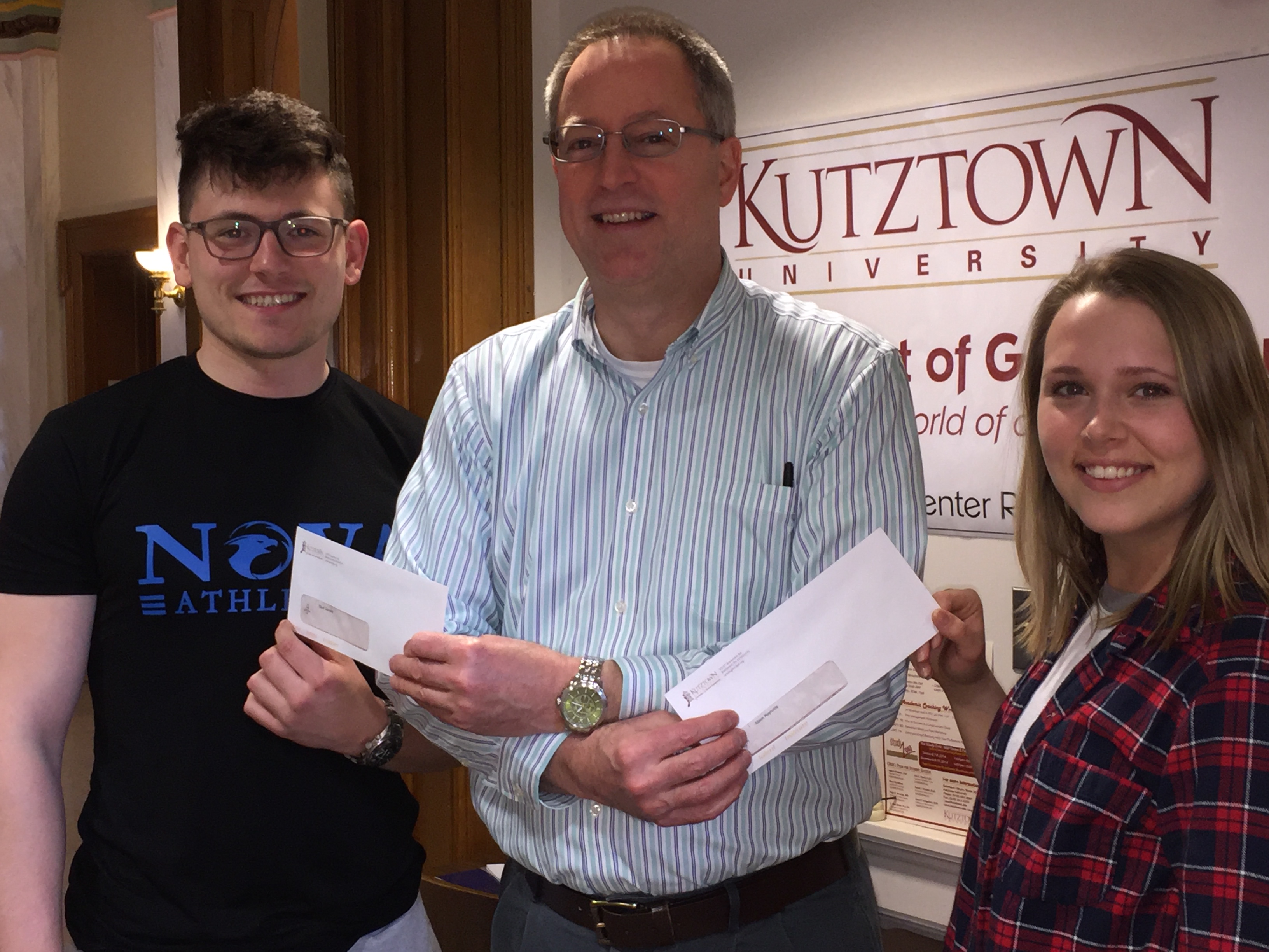 Two students being handed award envelopes by a male staff member at the 2018 Carrie Babb Presentation Awards
