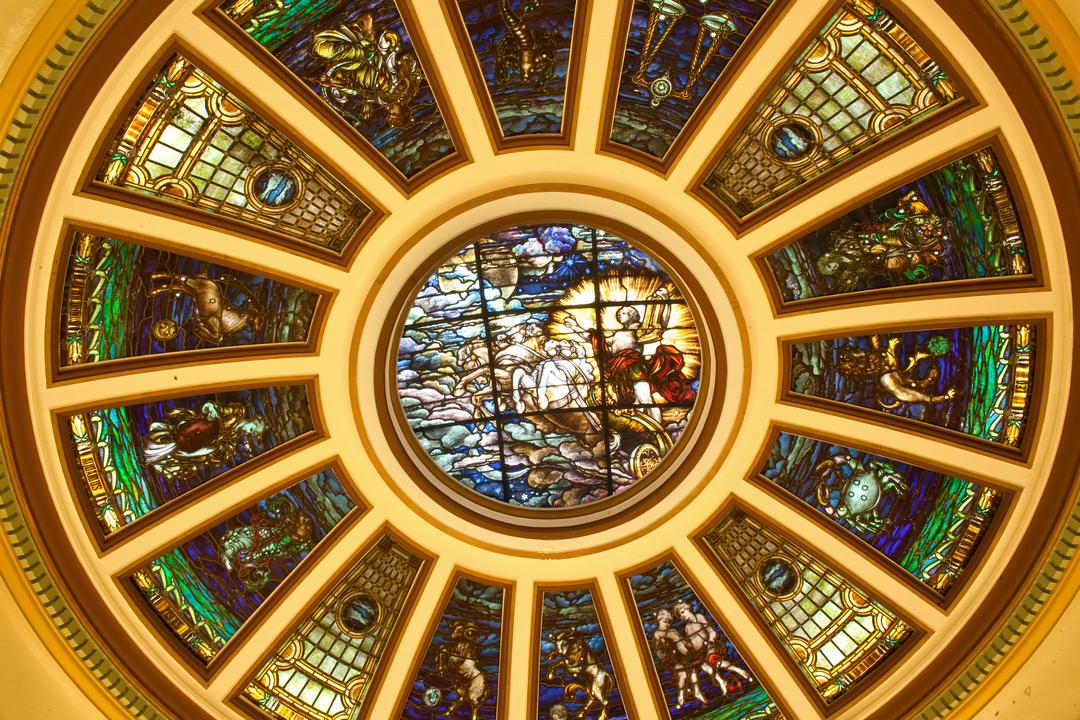 Dome ceiling with painted glass panels showing a man riding a horse in the clouds in the center