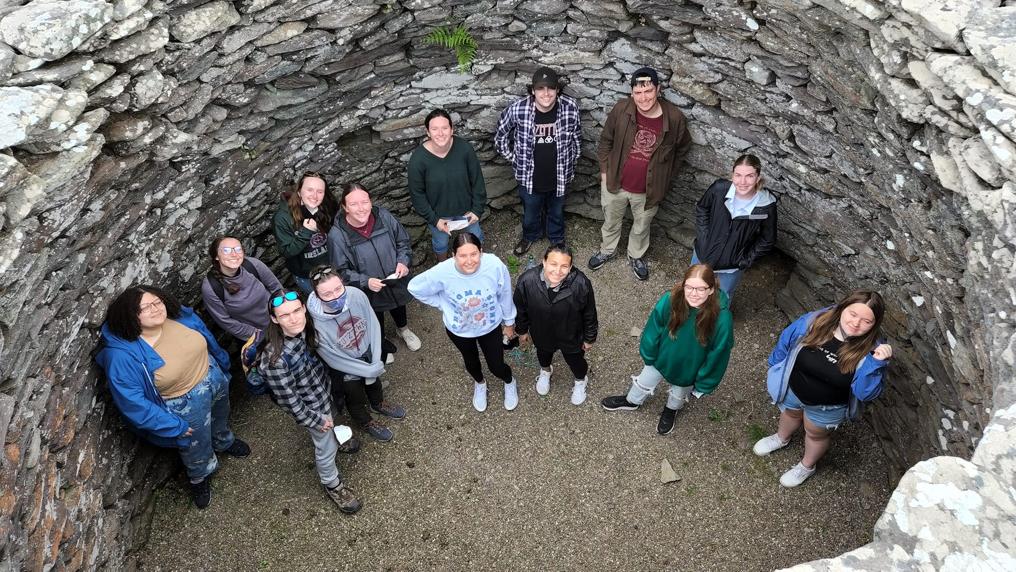 Overhead shot of smiling students in the bottom of a stone well 