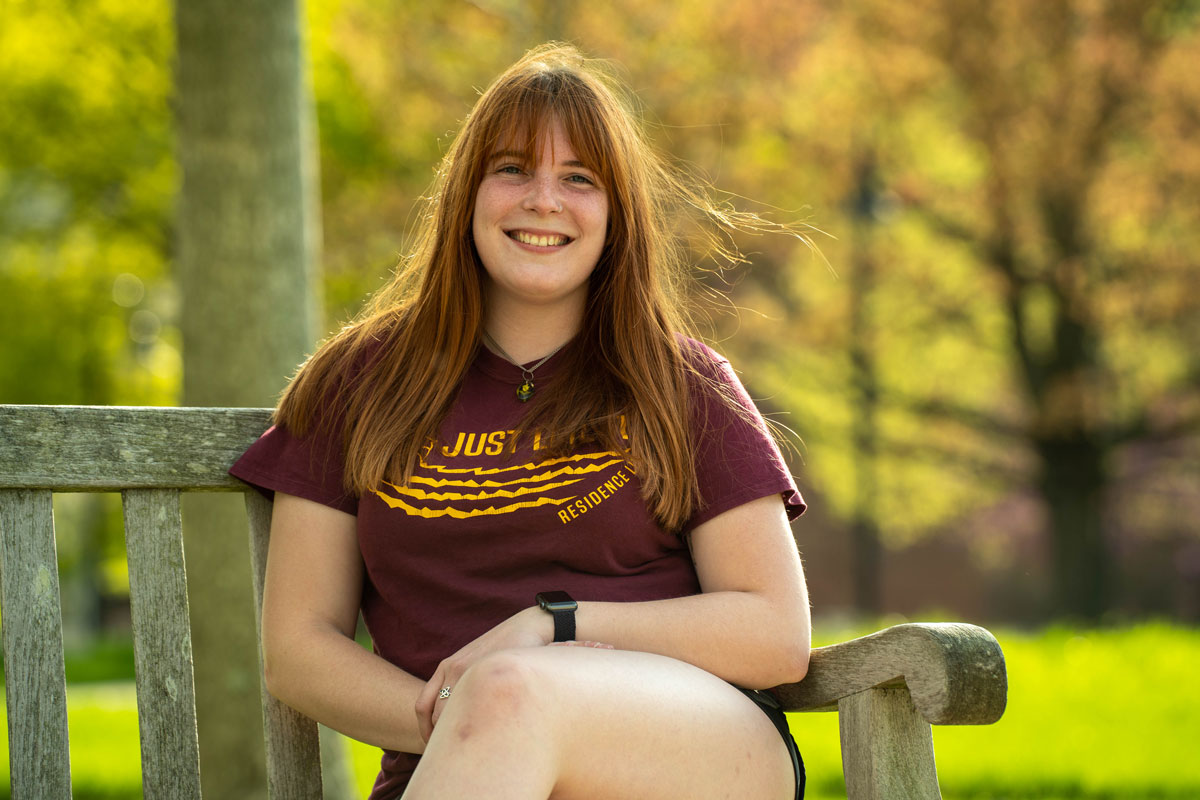 Female transfer student, Erin, sitting on a bench outside of Rohrbach library