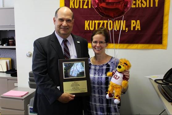 Kelly Hish holding her stuffed golden bear as Dr. Hawkinson presents her with the employee of the month award 
