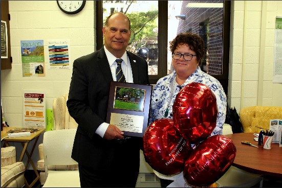 Anne Manmiller holding celebratory balloons as Dr. Hawkinson presents her with the employee of the month award 