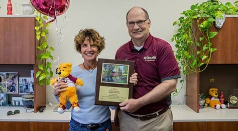 Brenda Booz and President Hawkinson holding the employee of the month award placard and gifts 