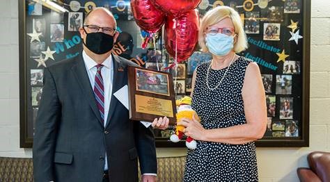 Lisa Grabowski and Dr. Hawkinson holding the Employee of the Month award placard, balloons, and stuffed golden bear between them 