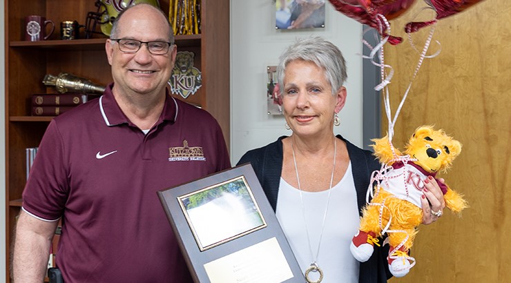 President Hawkinson presenting TBD with her Employee of the Month award plaque and gifts 