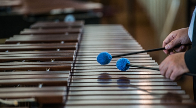 Closeup on a pair of hands playing a wooden marimba 