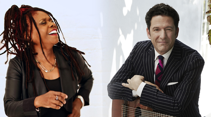 On the left, Catherine Russel is laughing with her head thrown back. On the right, John Pizzarelli smiles and leans on an acoustic guitar. 