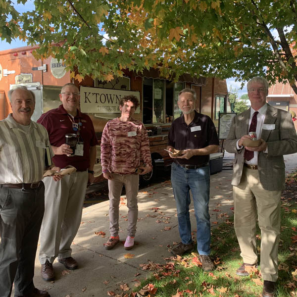 Faculty in front of food truck enjoying each other's company.