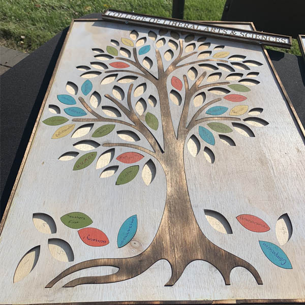 Display of community artwork that is a wooden tree with leaves.