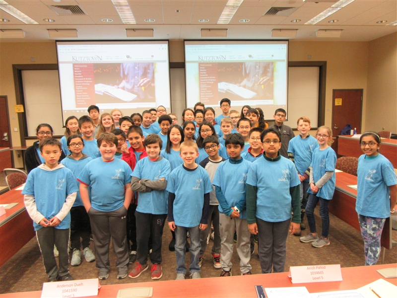 Math Kangaroo Participants standing in the center of a conference room and wearing blue event t-shirts