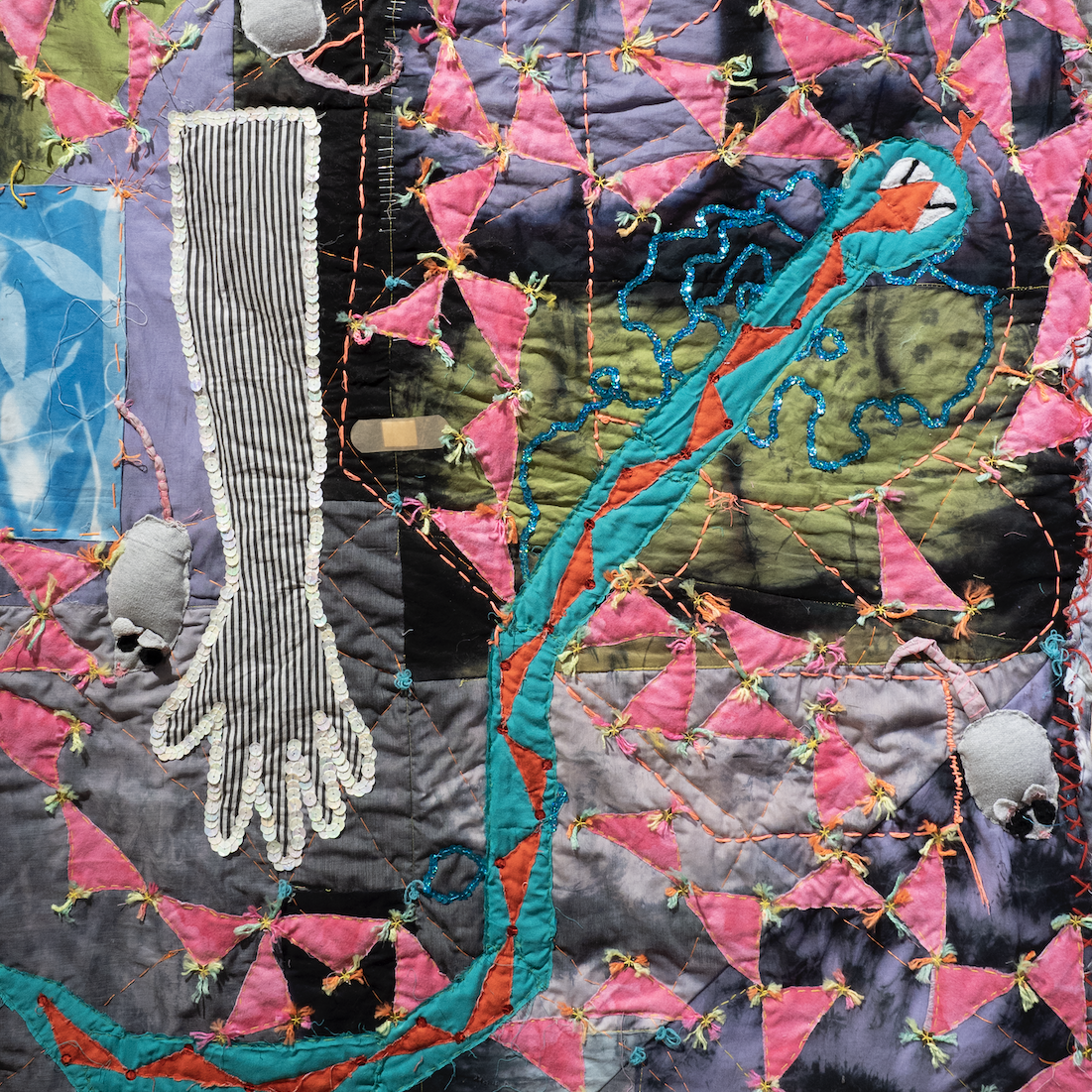 image of textile artwork with various shapes including triangles a hand a snake and mice