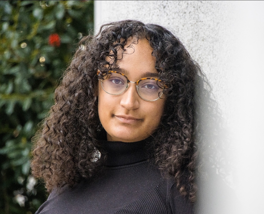 woman smiling leaning against wall wearing black shirt