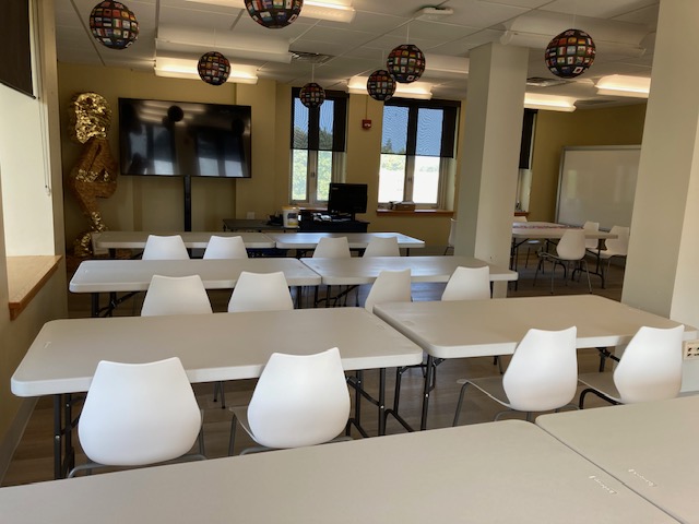 white tables and chairs in front of high TV in classroom