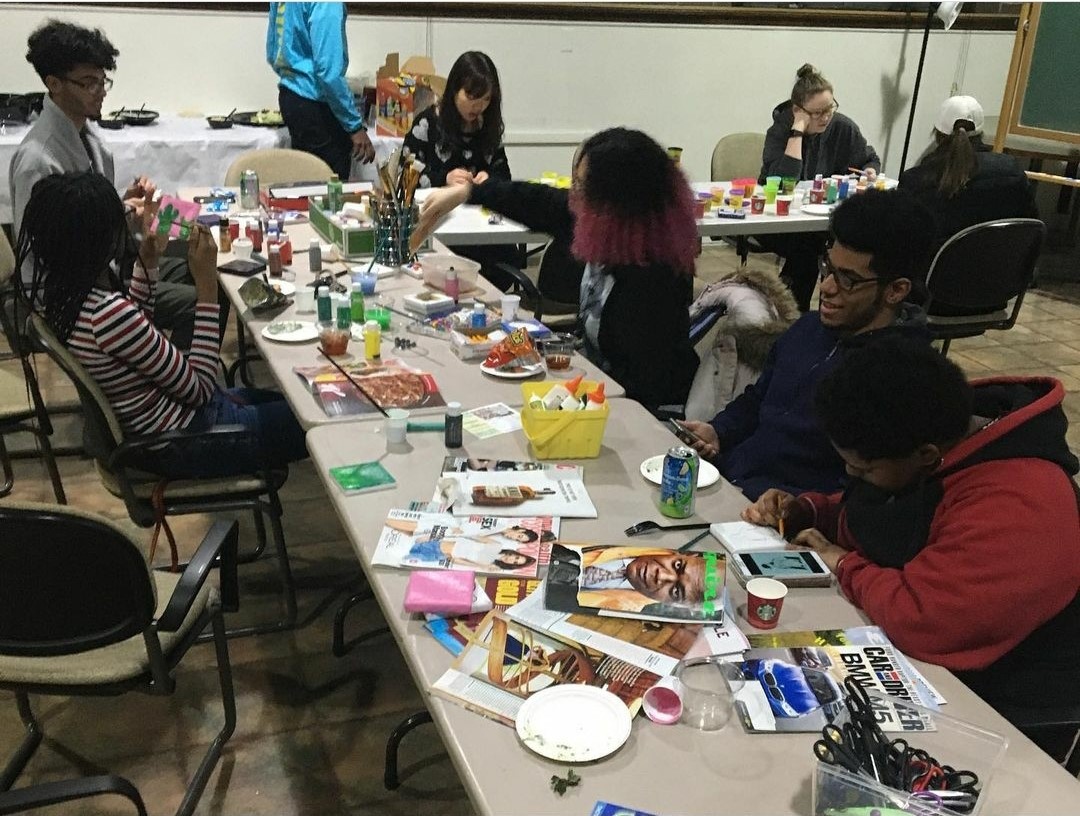 Students at a table in the Multicultural Center creating crafts with magazines