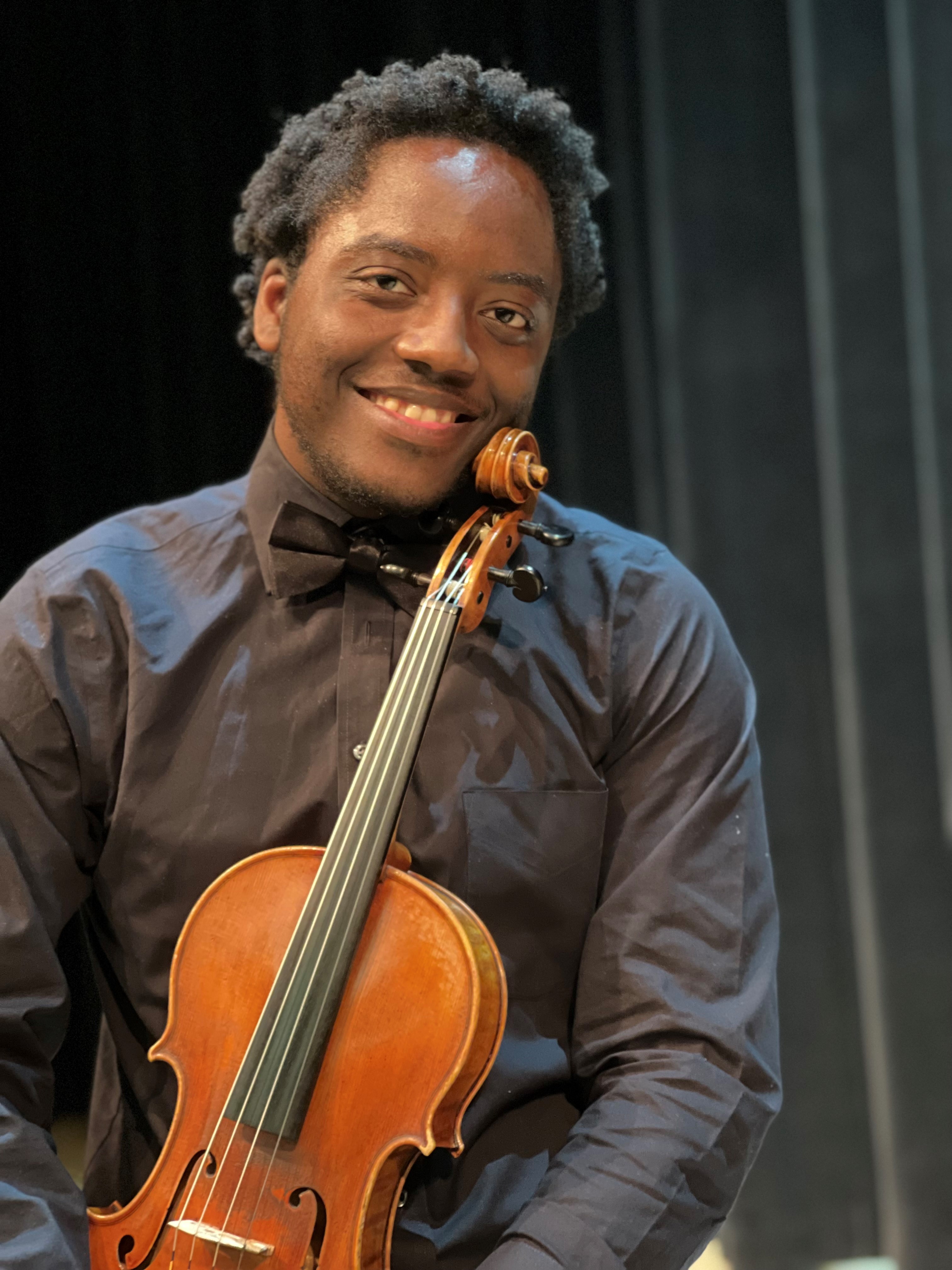 Rashawn Pressley smiling and holding his violin