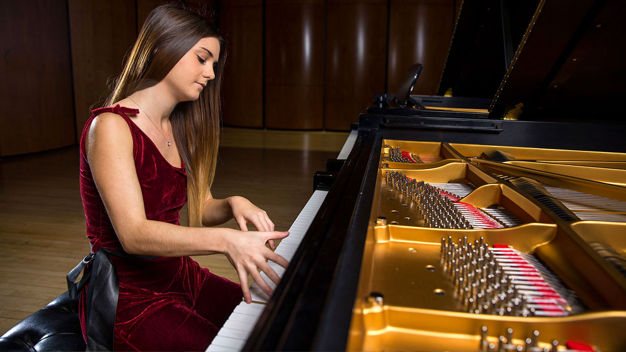 Sideview of a female student playing a grand organ piano 