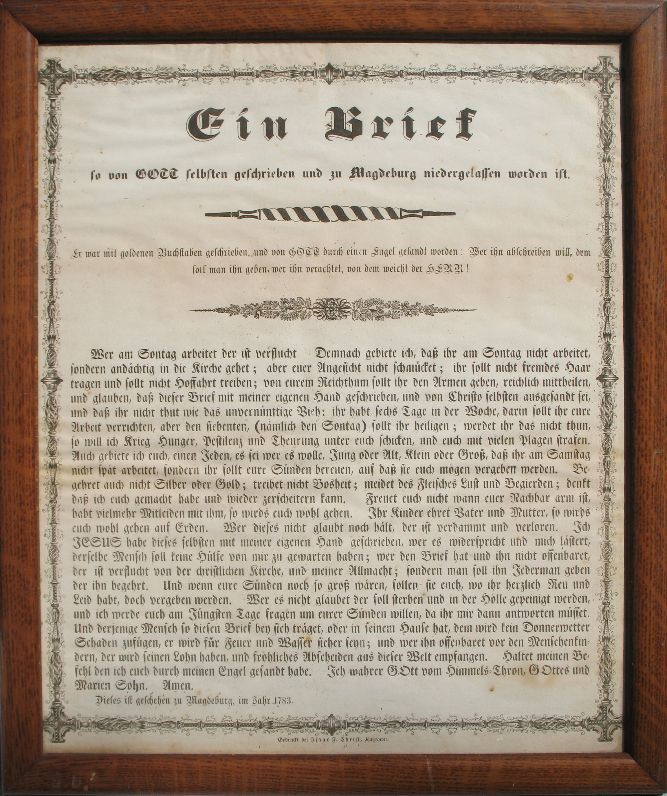 A rectangular document in a wooden frame, this Himmelsbrief is printed in German script with black ink. The border is decorated with black and gray columns that look to be wrought ironwork with vines extending off. There are two small decorative motifs before the main text. One is a black and white twisted shape while the other is a floral arrangement.