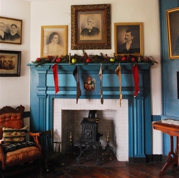 The teal mantle over the white stone fireplace in the parlor is decorated for Christmas