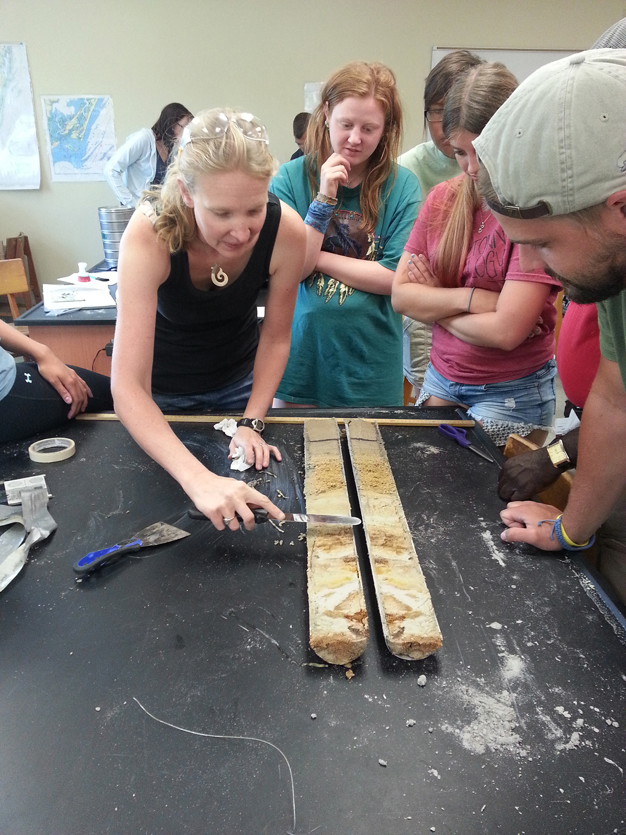Small group of students looking at a split sediment core in the lab. 