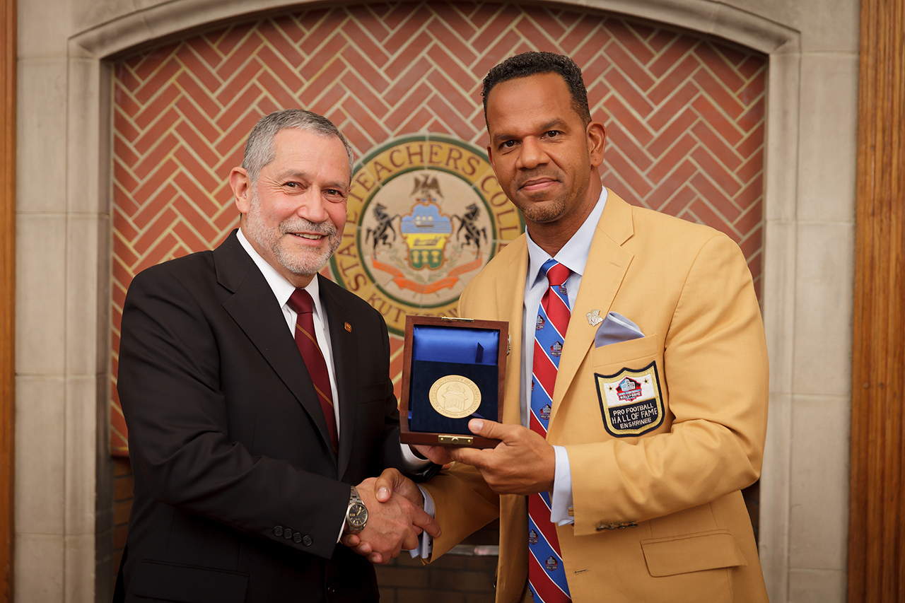 Interm President Dr. Carlos Vargas (left) presents Andre Reed (right) with the President's Medal.