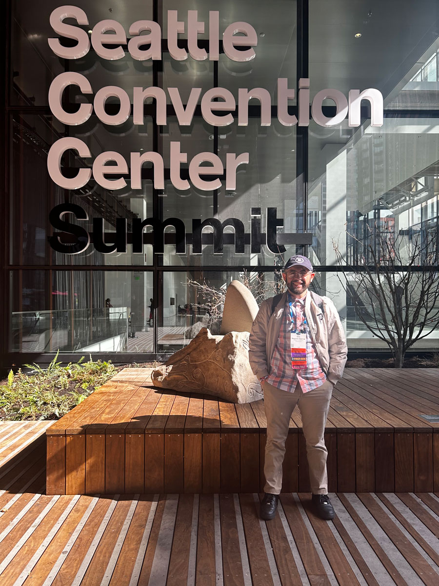 man standing in front of glass wall with a sign above him that reads Seattle Convention Center Summit