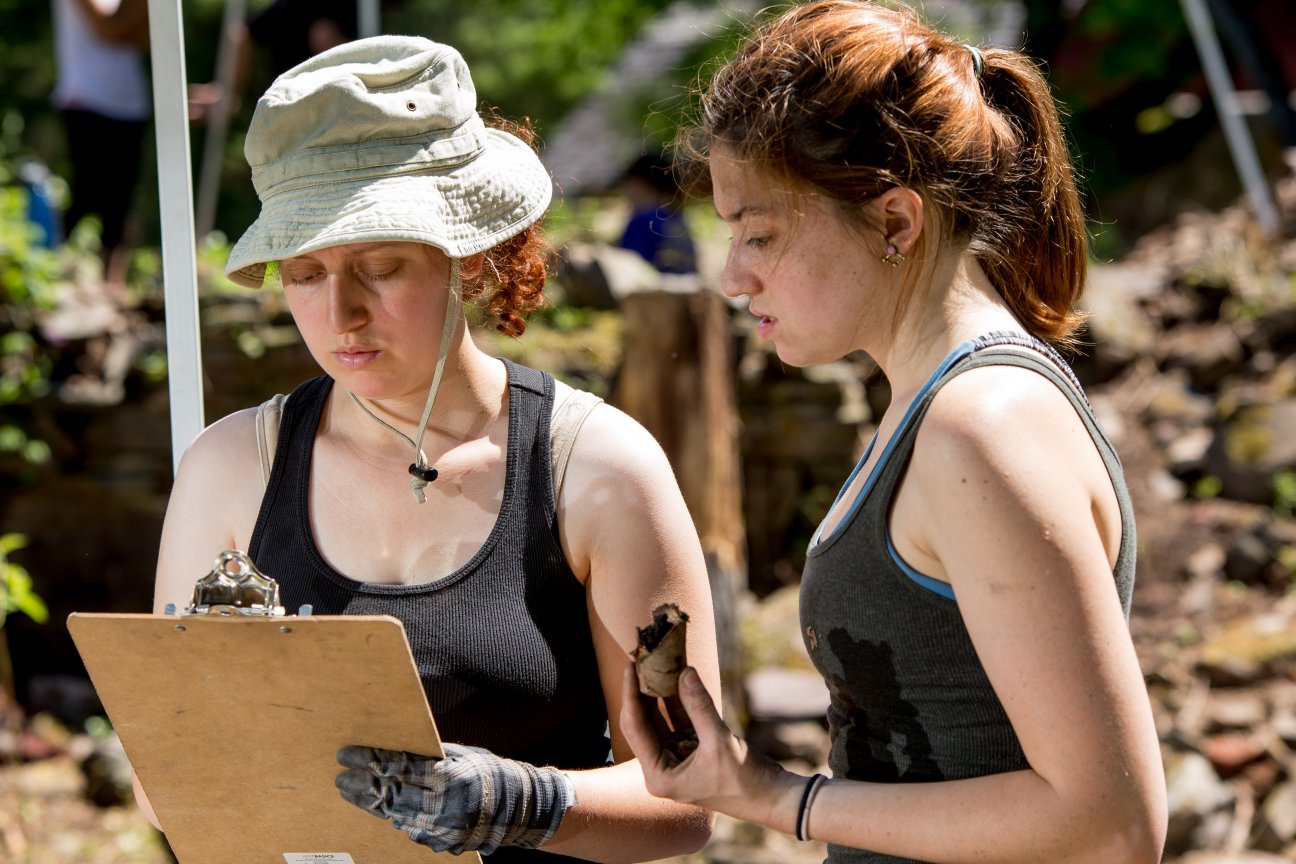 Two female students taking notes on samples in outdoor class