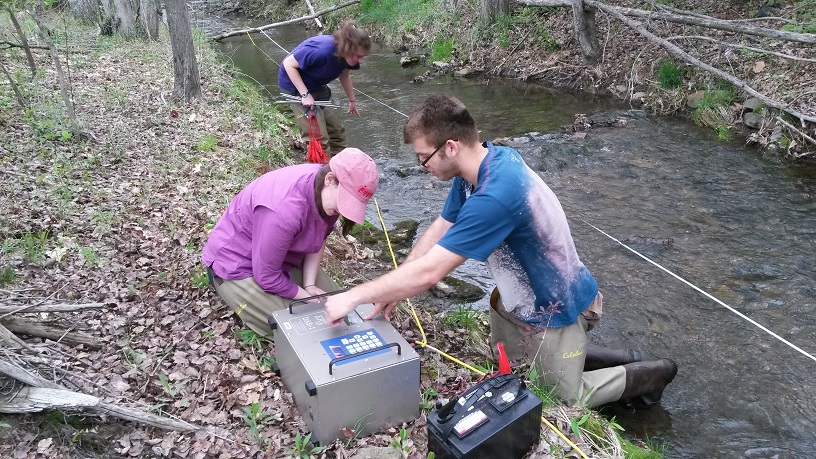 KU undergraduate students Sebastien Treciak, Alexandra Racosky, and Emily Snyder setting up imaging equipment on the bank of West Creek