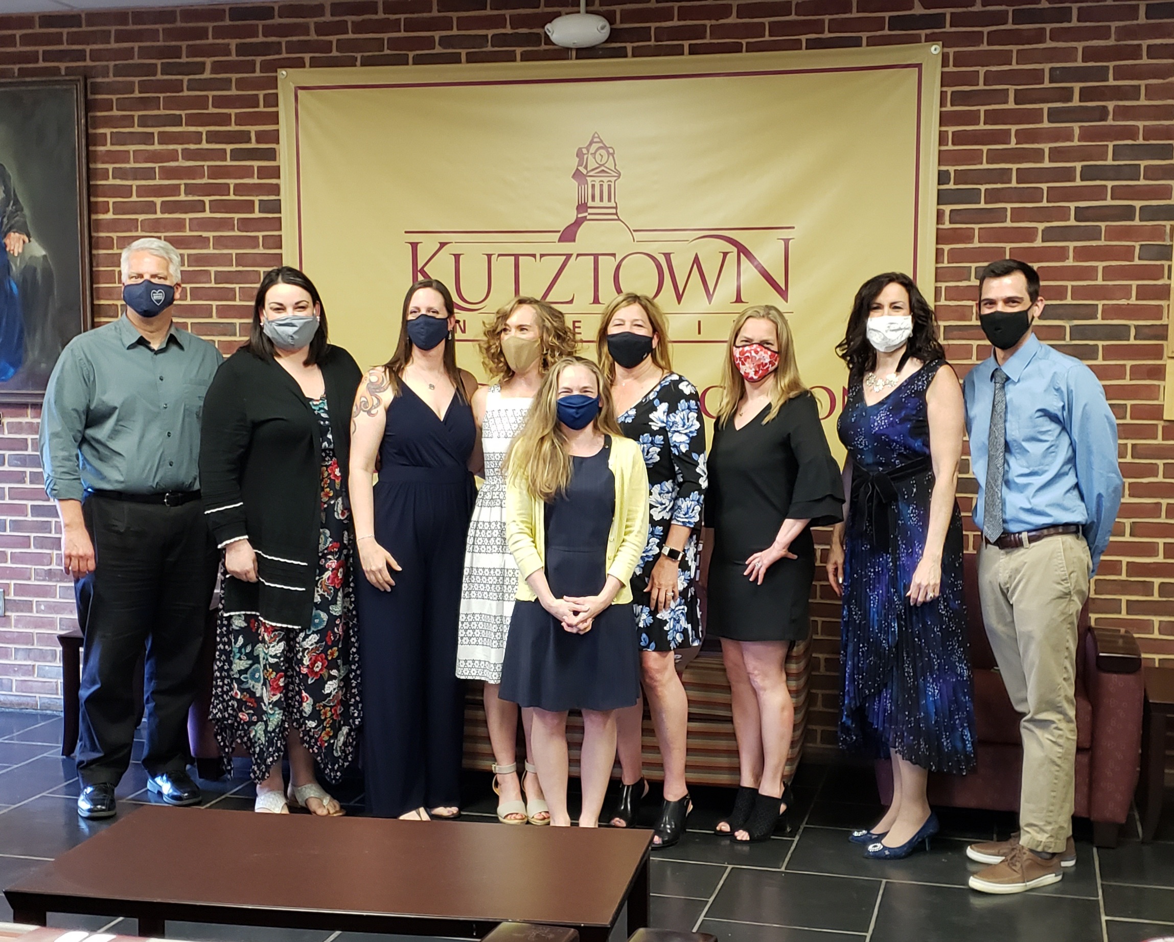 Group photo of Second Education Doctoral Cohort wearing masks and standing in front of a Kutztown University banner