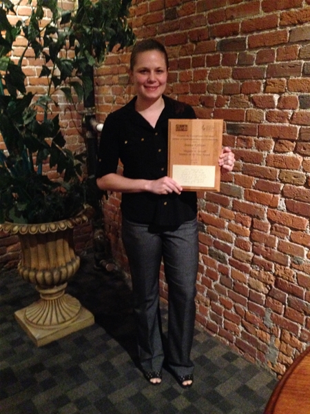 Female student holding 2016 National CEC Division on Visual Impairments and Deaf-Blindness Student of the Year Award on the steps, outside at night