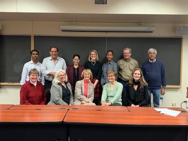 Group picture of faculty, standing in front of a blackboard in a workshop classroom 