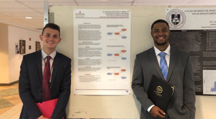 Deven Messner and Brandon McDonnaugh stand in front of their Research poster.