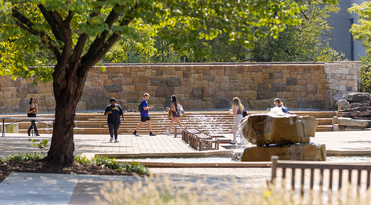 Students walking in front of waterfall at Alumni Plaza