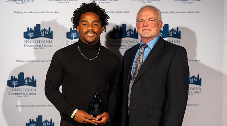 Taylor and Crider accepting award in front of media backdrop.