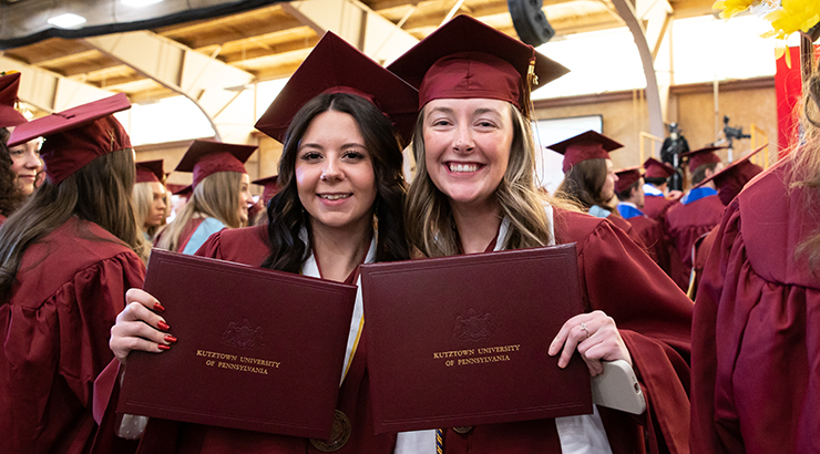 Students smiling holding diploma covers